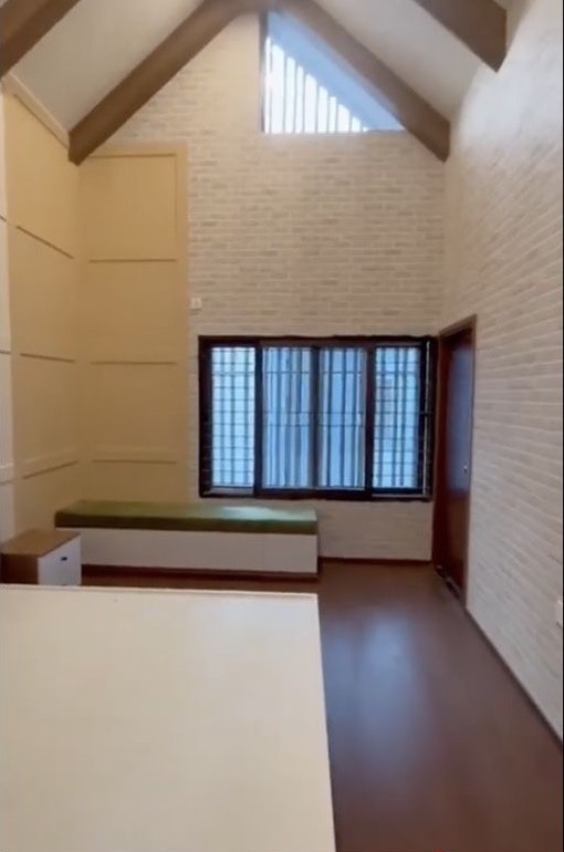 Completed Nature Vanaa modern-minimal villa atrium with a pitched ceiling, exposed timber beams and a built-in window seat